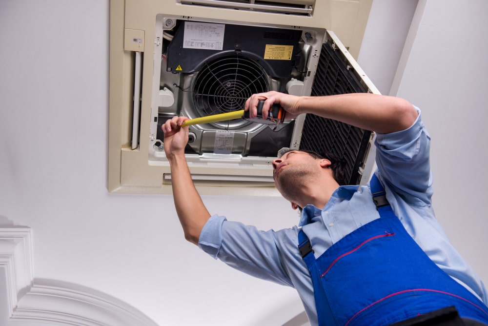 Male-technician-cleaning-air-conditioner-indoors-Duct-cleaning-Calgary